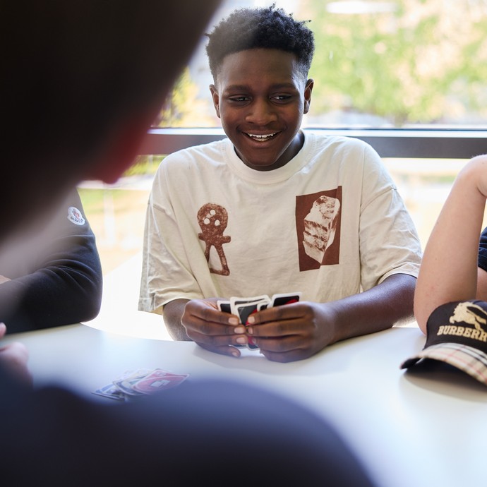 Lachende Lernende am Tisch (vergrößerte Bildansicht wird geöffnet)
