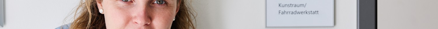 Portraitaufnahme von Werkstattleiterin Male Klein vor einer Tür mit Auschrift Fahrradwerkstatt