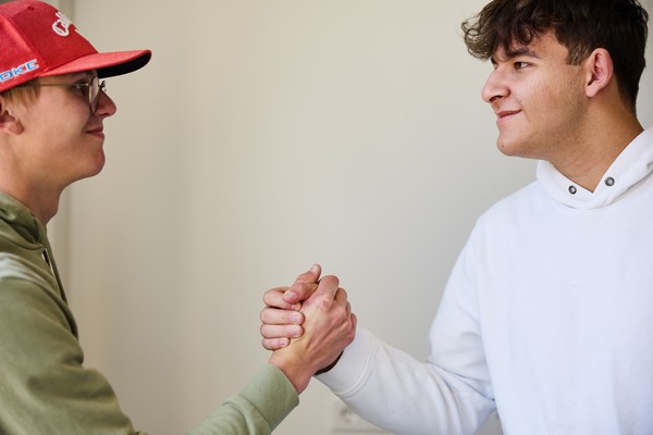 Zwei Schüler schauen sich an und geben sich die Hand.