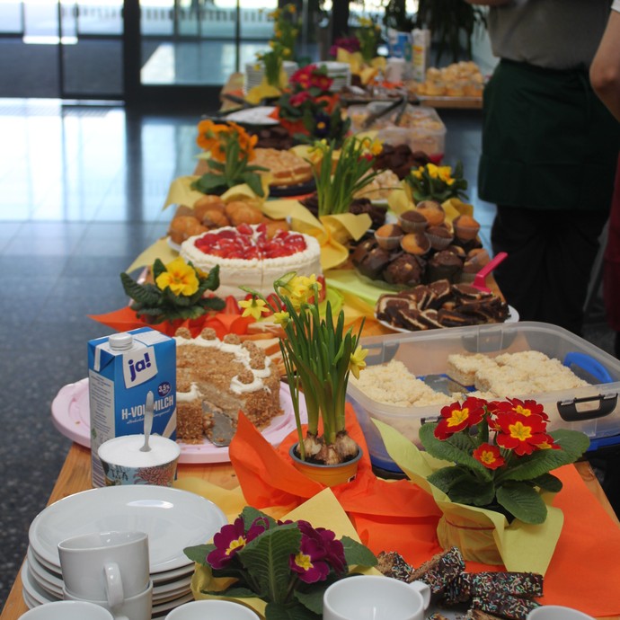 Ein Buffet mit Tassen, Tellern, Kuchen, Gebäck und Blumen (vergrößerte Bildansicht wird geöffnet)