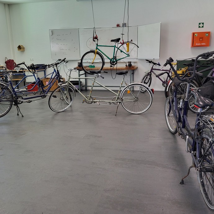 Sieben Fahrräder und ein Tandem in der Fahrradwerkstatt. (vergrößerte Bildansicht wird geöffnet)