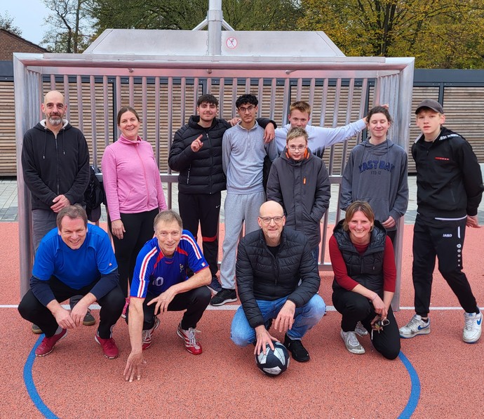 Lernende der 8. Klasse und Lehrkräfte vo rdem Tor auf dem Außensportplatz.