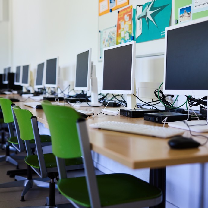 Computerraum mit Rechnern, Stühlen und Tisch (vergrößerte Bildansicht wird geöffnet)