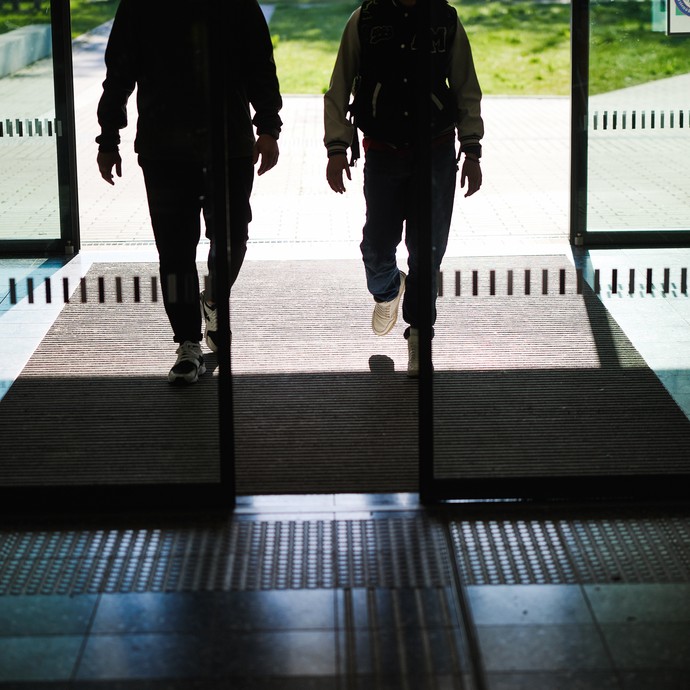 Zwei Personen am Schuleingang (vergrößerte Bildansicht wird geöffnet)