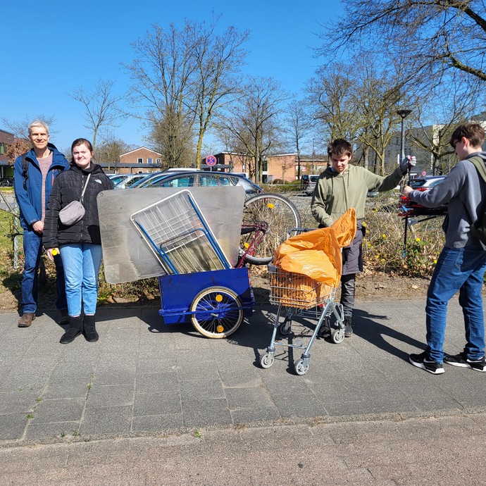 Drei Lernende stehen mit einer Lehrkraft neben gesammeltem Sperrmüll und Müll. (vergrößerte Bildansicht wird geöffnet)