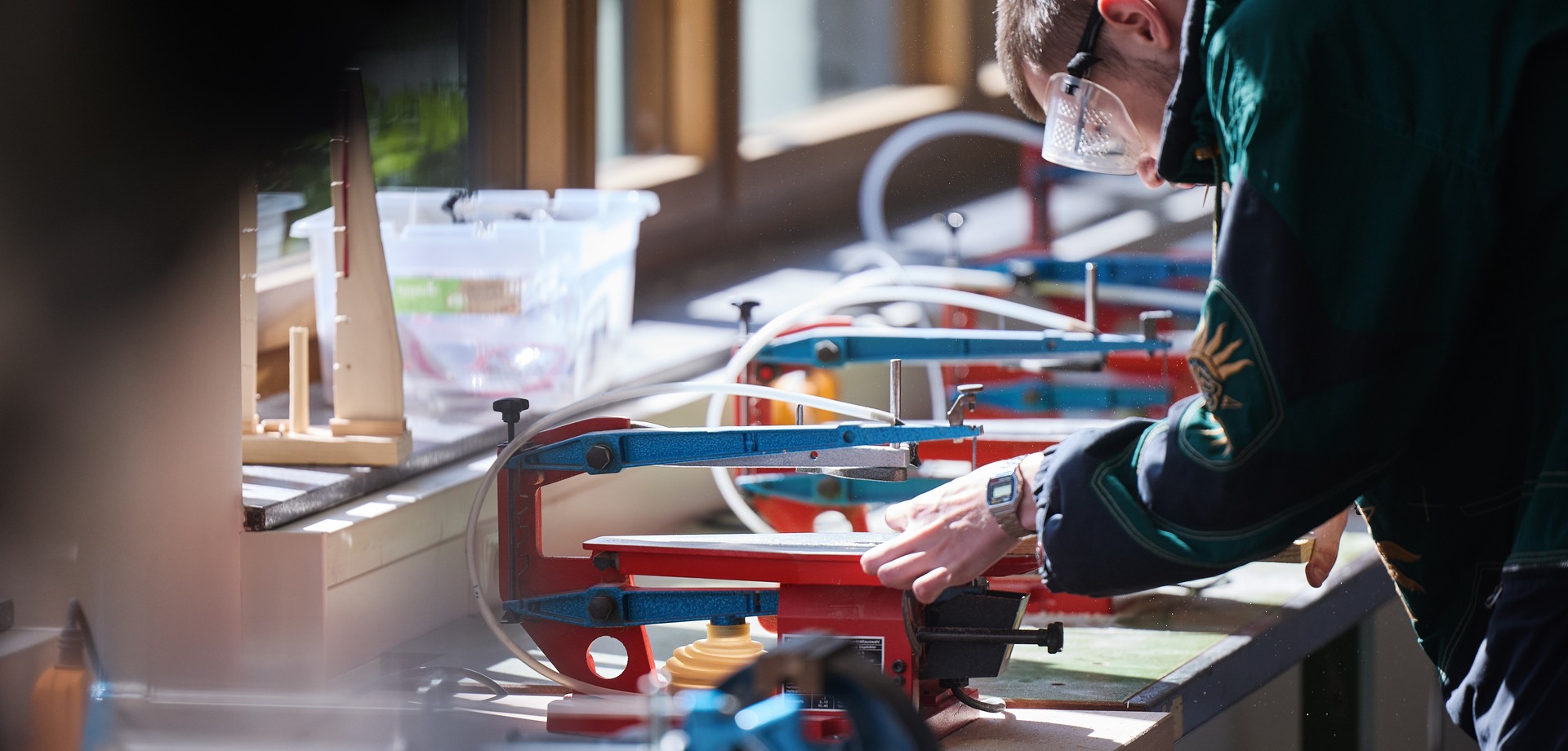 Ein Lernender an einer Säge mit Schutzbrille.