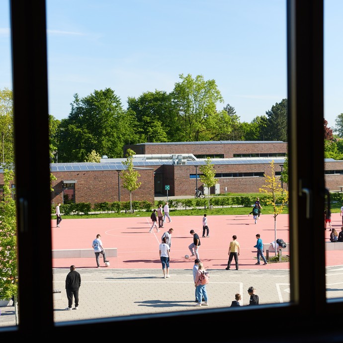 Lernende auf Sportplatz, die durch ein Fenster von innen fotografiert wurden. (vergrößerte Bildansicht wird geöffnet)