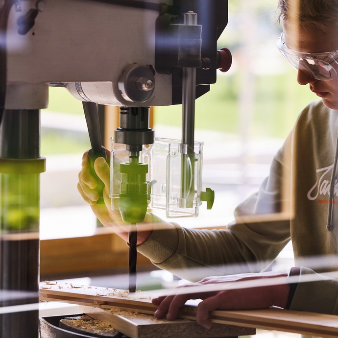 Ein Schüler mit Schutzbrille zersägt Holz an einer Bandsäge. (vergrößerte Bildansicht wird geöffnet)