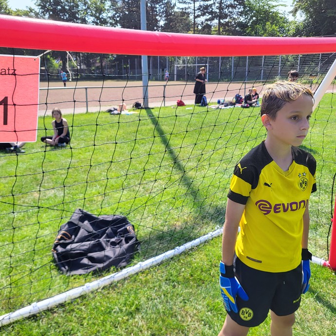 Ein Junge mit Fußballtricot steht im Tor. (vergrößerte Bildansicht wird geöffnet)